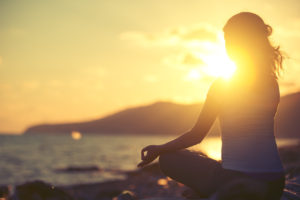 yoga in the beach. woman meditating in lotus pose on the beach at sunset